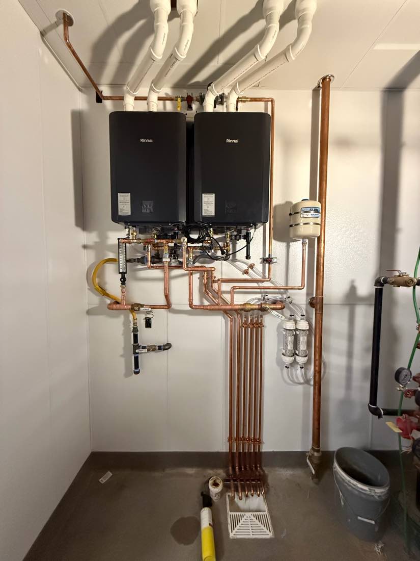 Two wall-mounted Rinnai tankless water heaters above a hand-built copper manifold.